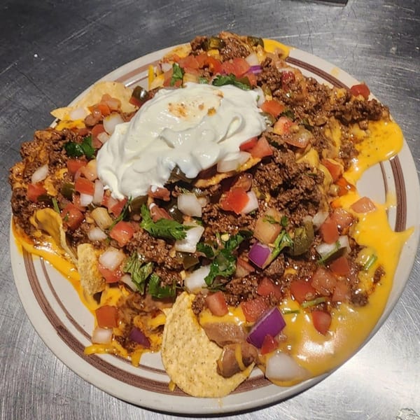 A plate of Waffle Shop's breakfast nachos with ground beef, cheese, pico de gallo, and sour cream.