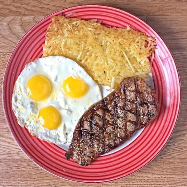 A Waffle Shop breakfast plate with steak, three fried eggs, and hash browns.