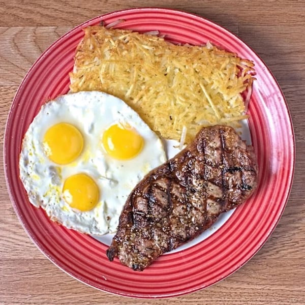 A Waffle Shop breakfast plate with steak, three fried eggs, and hash browns.